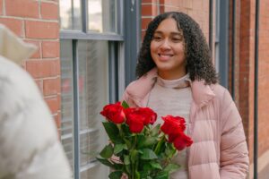 positive ethnic woman getting bouquet of roses from boyfriend